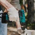 Person using Hand Drill on a Wooden Panel